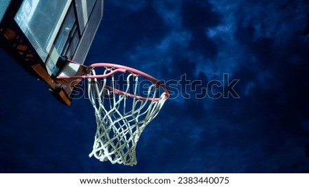 Basketball goal against the night sky, beat up and weathered, old and broken.