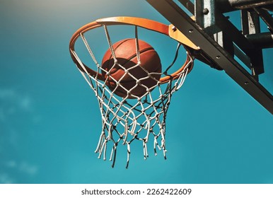 Basketball, goal and target in basket for sports match training on outdoor athletic court. Aim, score and winner with ball dunk in net at competition practice from low angle with blue sky. - Powered by Shutterstock