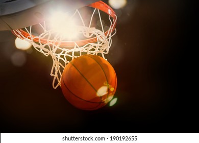 Basketball going through the basket at a sports arena (intentional spotlight)