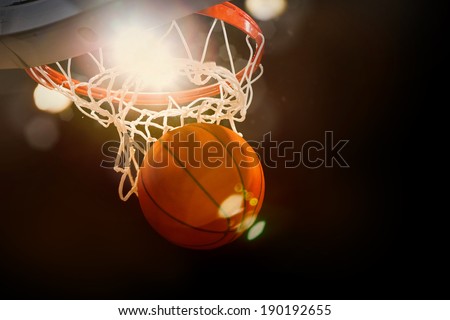 Basketball going through the basket at a sports arena (intentional spotlight)