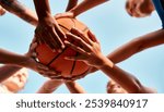 Basketball, hands together and players with ball for fitness, support or motivation in outdoor activity. Sports game, huddle and group of people in low angle for teamwork, exercise or training match