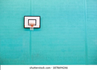 Basketball hoop against a turquoise brick wall at a gym. - Powered by Shutterstock