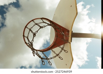 Basketball hoop with chain mesh during a blue sky day with clouds overhead. Shot on 35mm film. - Powered by Shutterstock