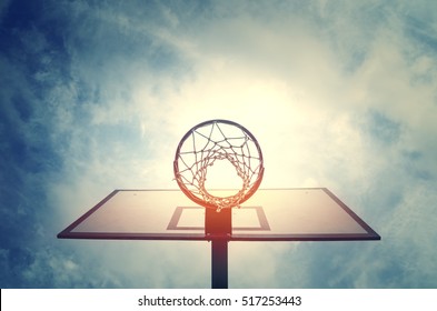 Basketball hoop on basketball court under blue sky with clouds