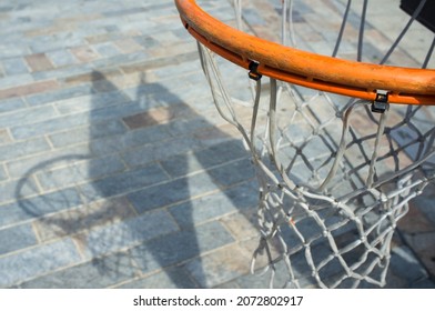 Basketball Hoop Proyecting Shadow Over Cobble Stone Road Surface. Closeup