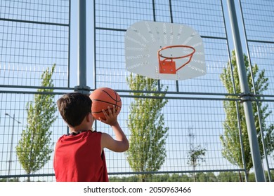 Basketball kid player throwing the ball to the basket.