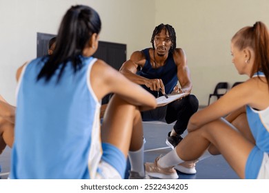 Basketball male coach discussing strategy with female players during team meeting. coaching, teamwork, training, sports, discussion, women - Powered by Shutterstock