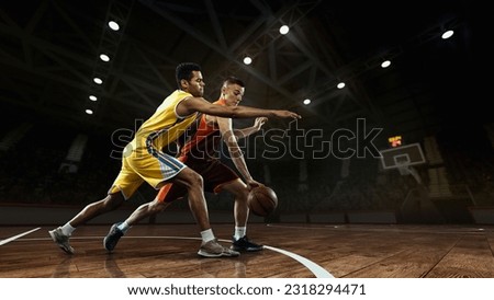 Basketball match. Two basketball players in motion with ball at 3d model sports arena. Concept of competition, rivals, games, plays, sport and ad. Athletes wearing team colors sportswear