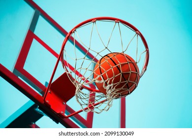 A basketball in the net. The fly ball is in the ring. A sports game. Conceptual: victory, success, hitting the target, sport. Successful ball throw.