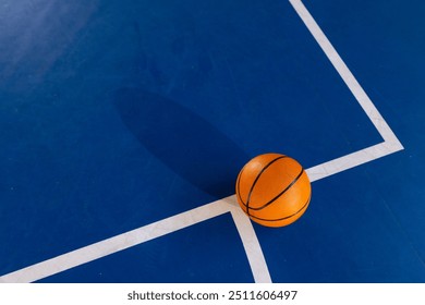 Basketball on court, resting on blue floor with white lines, copy space. Sports, game, athletics, equipment - Powered by Shutterstock