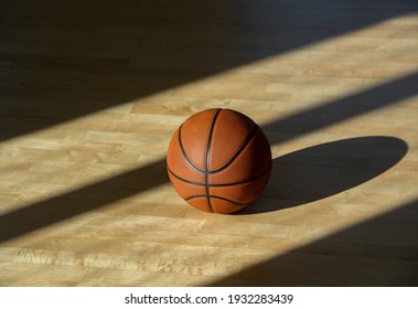 Baloncesto en el suelo de una cancha de madera dura con luz natural. Concepto en línea de entrenamiento