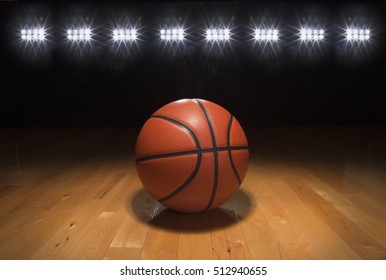 A Basketball On A Wood Floor Beneath Bright Arena Lights