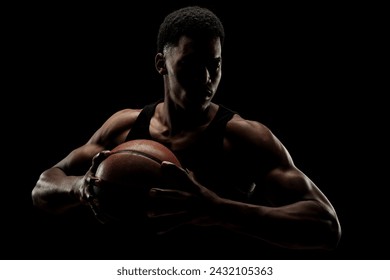 Basketball player holding a ball against black background. Serious concentrated african american man. - Powered by Shutterstock