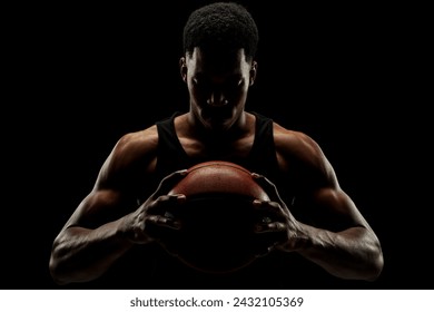 Basketball player holding a ball against black background. Serious concentrated african american man. - Powered by Shutterstock