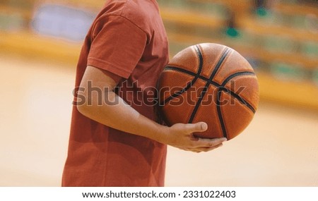 A basketball player holding a ball during a training session. Youth basketball team on practice unit. Basketball training session for school kids. College boys improving basketball skills