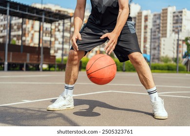 A basketball player in mid-dribble, focused on controlling the ball during an outdoor game on a city court.

 - Powered by Shutterstock