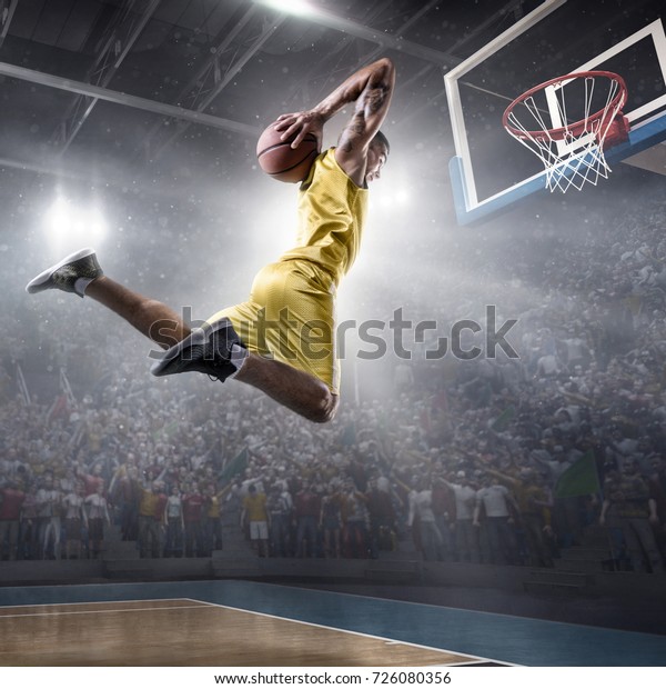 Basketball player on big professional arena\
during the game. Basketball player makes slam dunk. Player wears\
unbranded clothes.