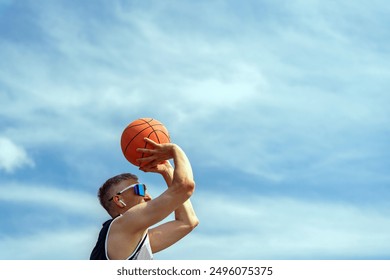 A basketball player poised to take a shot, concentrating under the expansive sky.

 - Powered by Shutterstock