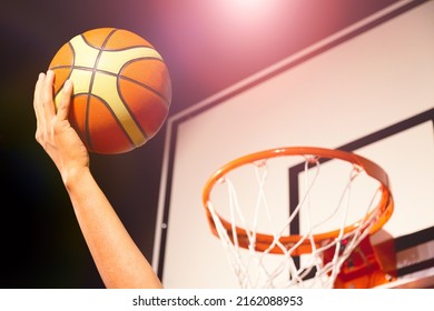 Basketball player putting basketball ball into the hoop in air