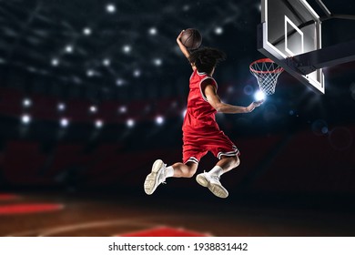 Basketball player in red uniform jumping high to make a slam dunk to the basket - Powered by Shutterstock