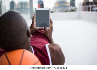 Basketball player using digital tablet while relaxing on terrace - Powered by Shutterstock