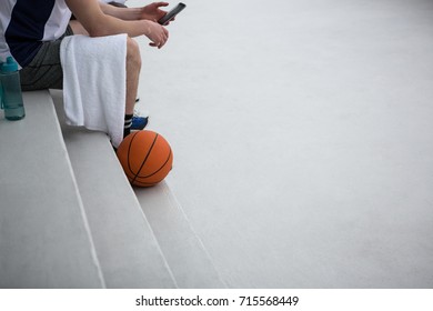 Basketball player using mobile phone on terrace - Powered by Shutterstock