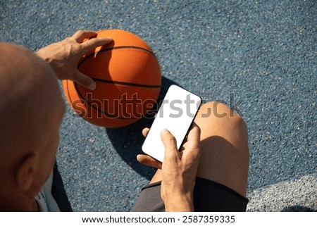 Basketball player using smartphone and texting social media during game interval, Outdoor training. View from above. Close up.