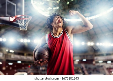 Basketball player wins the match at the basket stadium full of spectators.
