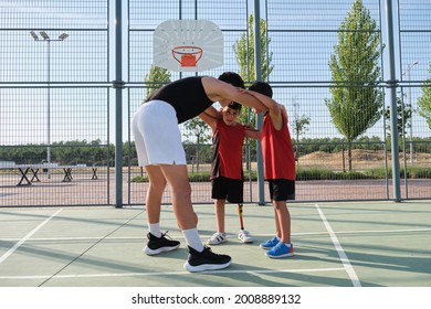 Basketball players gathering around their coach, one of them has a leg prosthesis. Coach motivating kids during time out. - Powered by Shutterstock