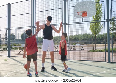 Basketball players high fiving with their coach, one of them has a leg prosthesis. Coach motivating kids during time out.