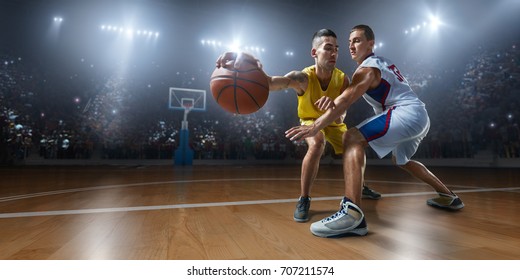 Basketball players on big professional arena during the game. Players fight for the ball. They are wearing unbrand clothes.