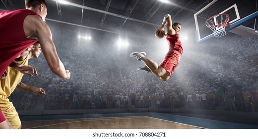 Basketball players on big professional arena during the game. Basketball player makes slam dunk. Players are wearing unbrand clothes.