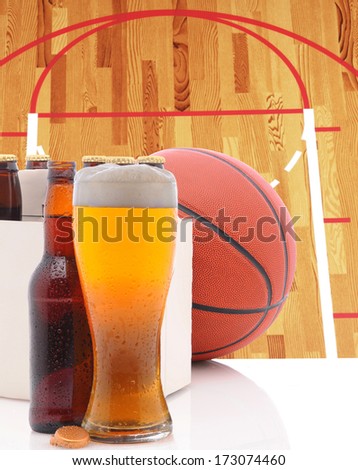 A Basketball Six Pack of Beer Bottles and a Glass of Ale on a white table top with Court in background. 