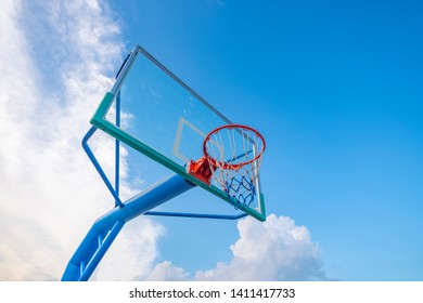 The basketball stands on the outdoor basketball court are under the blue sky and white clouds.