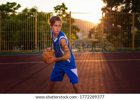 Similar – Teenage boy holding a basketball on a court