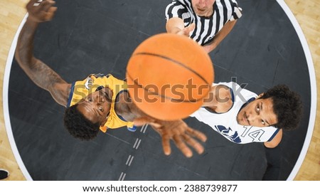 Basketball Tournament Final: Diverse Yellow and White Teams Compete at Center Court for Jump Ball that Starts the Game. Athletic Sportsmen Reach for the Ball. Top Down Cinematic Shot.