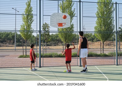 Basketball Trainer Showing How To Shoot Basketball To A Two Children, One Of Them Has A Leg Prosthesis. Coach Training Two Kids.