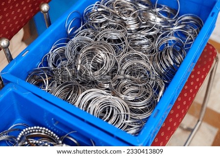 Baskets with batch of kara sikh bangles for sale in Gurudwara Bangla Sahib temple, many steel bracelets shopping for tourists, kara bangles symbol of unbreakable attachment and commitment to God