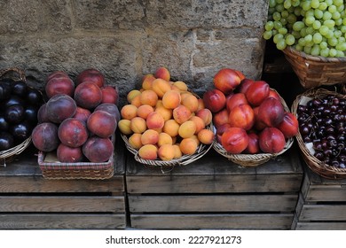 Baskets of fresh peaches, plums, apricots, cherries, grapes and nectarines set on wooden crates in a produce market in Italy.  - Powered by Shutterstock
