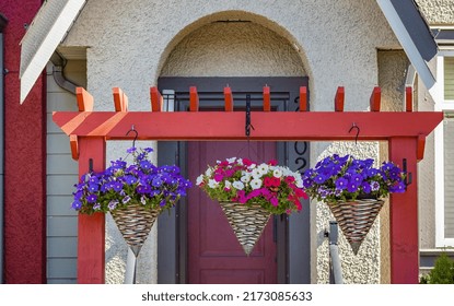 Baskets Of Hanging Colorful Flowers On Entrance Gate Of House. Summer Flowers In Ornamental Plant. Street Photo, Nobody, Selective Focus