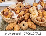 Baskets overflowing with different kinds of bread variety of shapes in local bakery setting.