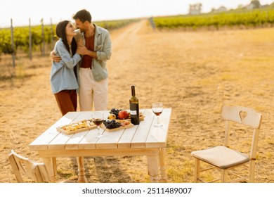 Basking in the warm sunlight, a joyful couple embraces as they revel in a delightful picnic among the grapevines, savoring wine and gourmet treats - Powered by Shutterstock