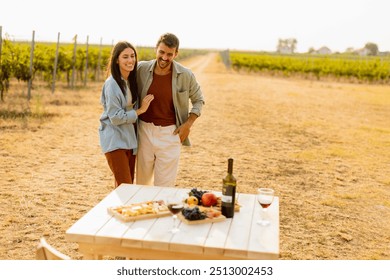 Basking in the warm sunlight, a joyful couple embraces as they revel in a delightful picnic among the grapevines, savoring wine and gourmet treats - Powered by Shutterstock