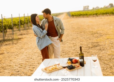 Basking in the warm sunlight, a joyful couple embraces as they revel in a delightful picnic among the grapevines, savoring wine and gourmet treats - Powered by Shutterstock