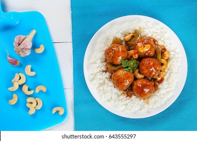 Basmati Rice With Chicken Or Turkey Meatballs Stewed With Green Bell Pepper, Cashew Nuts, Onion, Soy Sauce, Chinese Cooking Wine And Spices On White  Plate On Old Wooden Table, View From Above