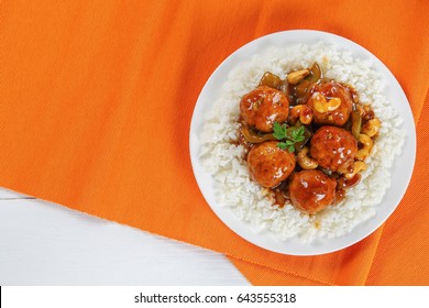 Basmati Rice With Chicken Or Turkey Meatballs Stewed With Green Bell Pepper, Cashew Nuts, Onion, Soy Sauce, Chinese Cooking Wine And Spices On White  Plate On Old Wooden Table, View From Above