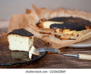 Basque burnt cheesecake slice with a burnished exterior and a creamy custardy interior on a brown glass plate. Spanish dessert for breakfast - Shutterstock ID 2133632869