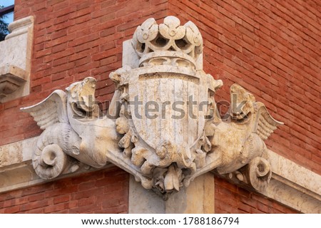 Bas-relief of old coat of arms shield on the entrance with fcatalan flag, dragons and crown