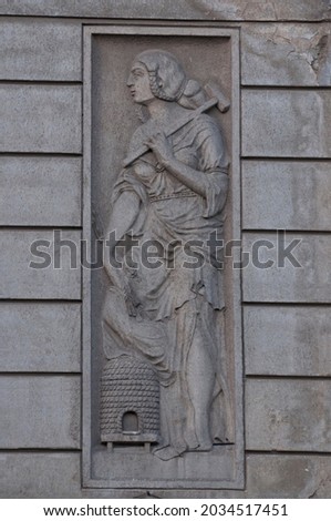Bas-relief with working woman who has a hammer and ears of wheat.