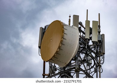 Bass drum style microwave antennas on tall tower, closeup. 5G Cellular communication for mobile phone and video data transmission. Telecommunication connection point against grey cloudy sky